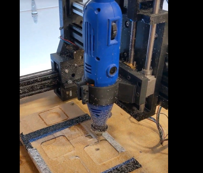A converted CNC router with a blue spindle cutting a pocketed pattern into plywood.